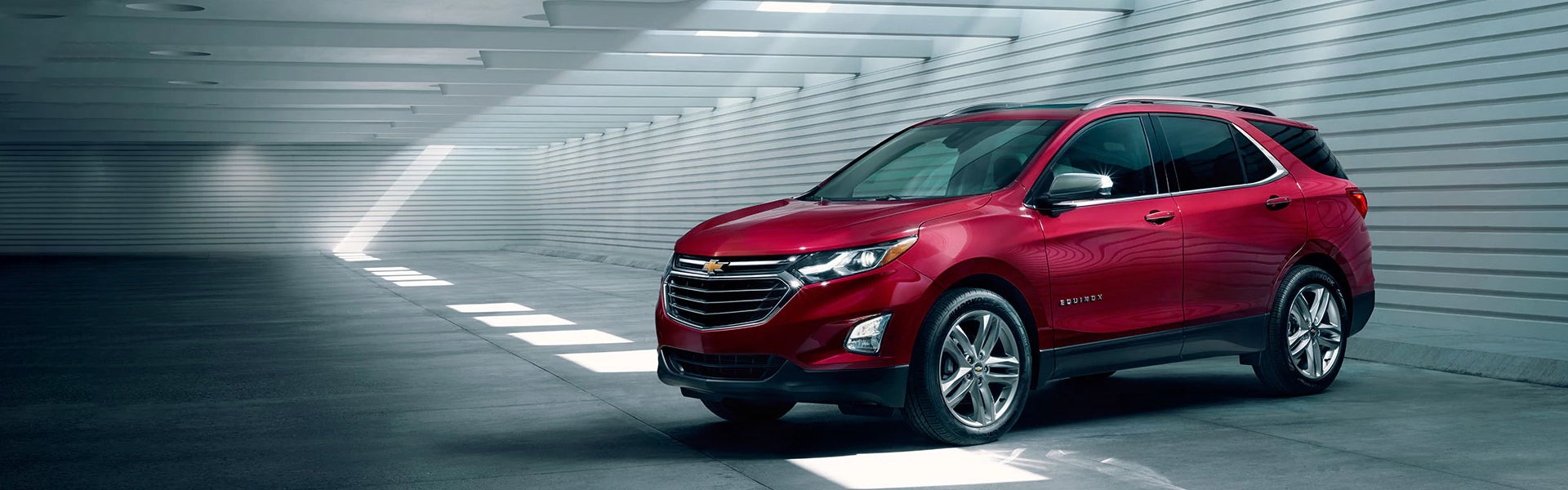 A red Chevrolet Equinox SUV parked in a modern garage with sleek lighting and bold styling.