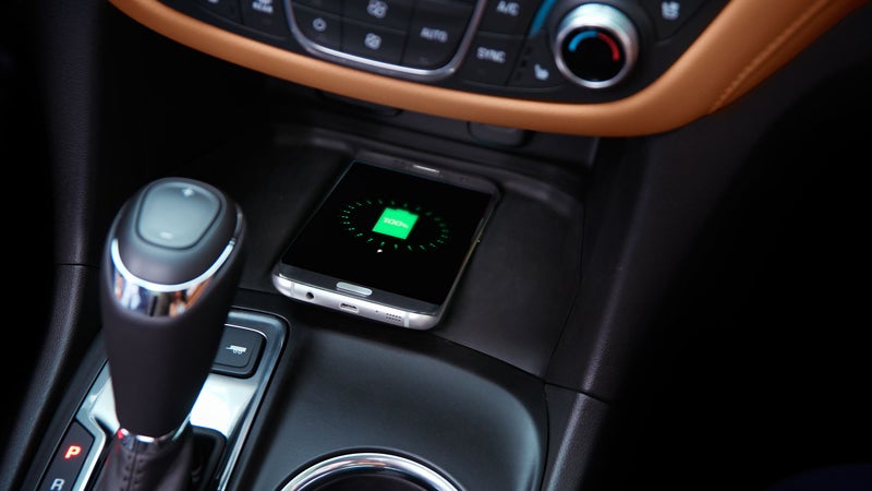 Center console with gear shift and a smartphone on a wireless charging pad.