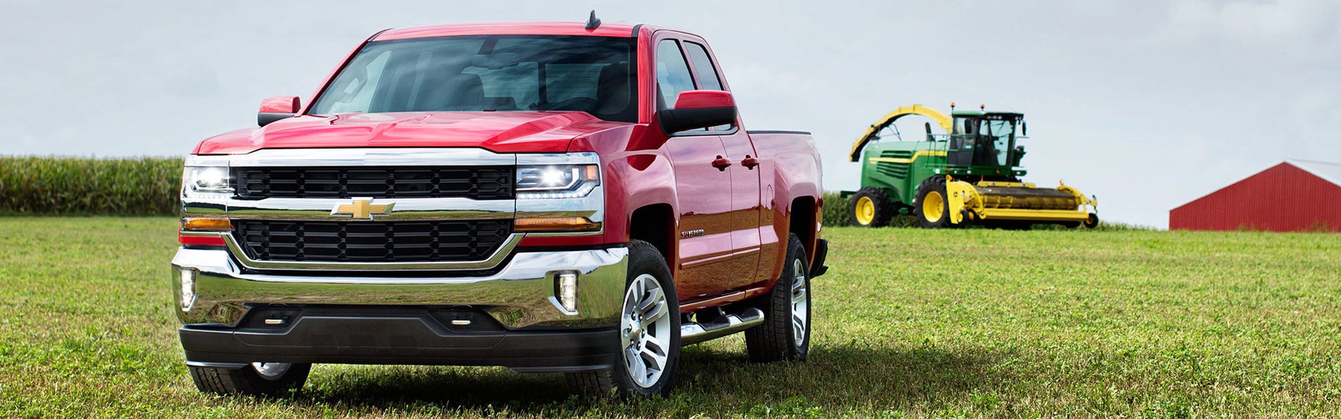 A red Chevrolet Silverado pickup truck parked on a grassy field