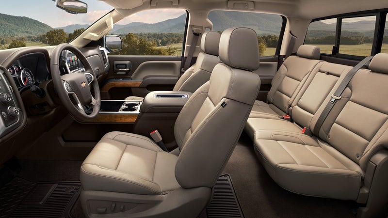 Interior view of a Chevrolet Silverado, showcasing beige leather seats, a modern dashboard, and a spacious cabin with woodgrain accents.