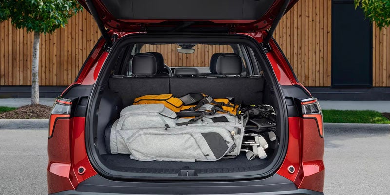 Open trunk of a red Chevrolet SUV with travel gear inside.